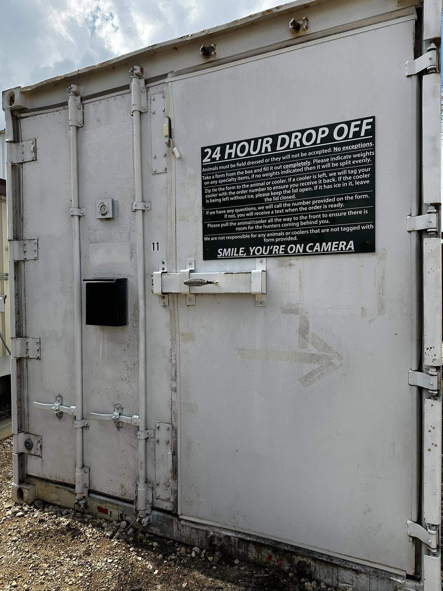 J's Processing 24-hour drop-off cooler with the drop-off instructions sign and black form box on the door